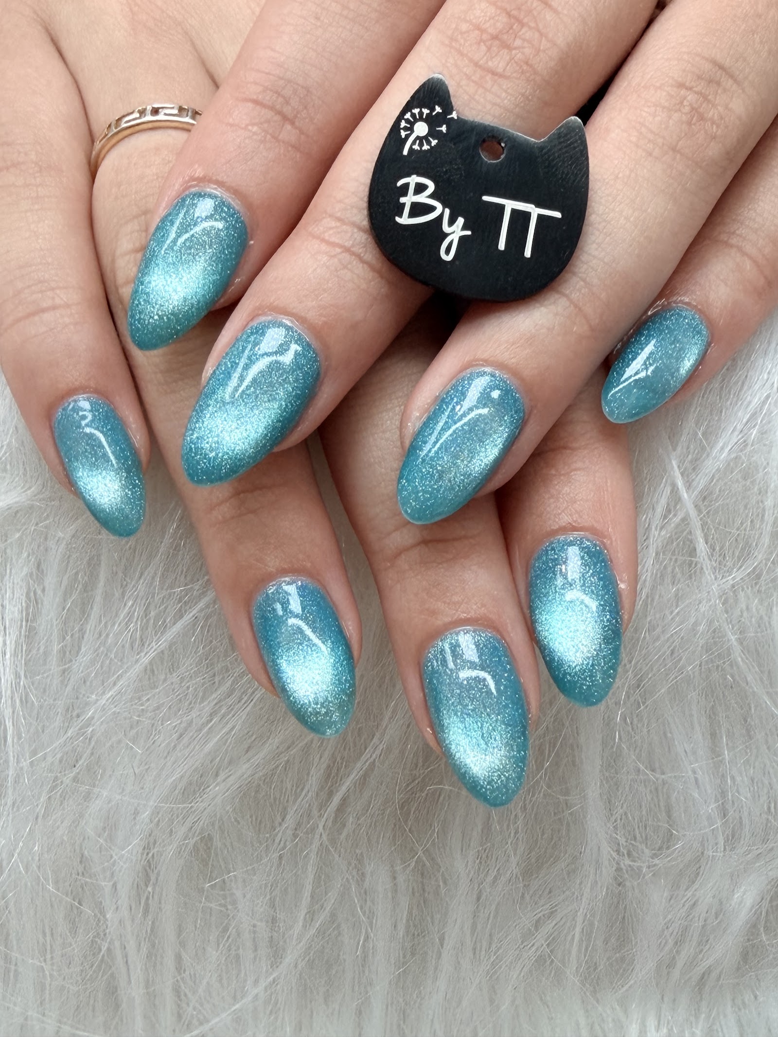 Almond nails in a shimmering aqua cat-eye gel that catches the light in a single bright stripe.